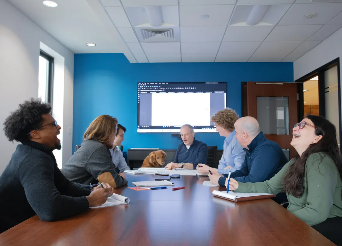 Team laughin in conference room with dog